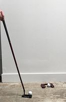 Full travel putter assembled with ball and wooden cup on floor showing usage and scale.