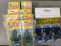 Photo of 72 hanging Little Trees Royal Pine air fresheners with 3 packs of Little Trees Vent Wrap air fresheners and white box of 4 cans of Little Trees Green Apple fragrance air fresheners.