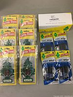 Package with 10 Little Trees Royal Pine hanging air fresheners, 4 packs of Little Trees New Car Scent vent wraps (4 units each), and a box likely containing fiber cans.