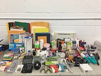 Wide view of assorted office supplies including folders, envelopes, calculators, tape, pens, staplers, and various labelling and organizing tools on display.