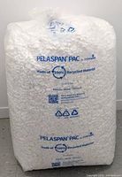 Large sealed transparent bag filled with white Pelaspan PAC loose fill packaging peanuts made from 100% recycled material