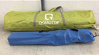 Green QOMOTOP tent bag with logo and grey carry straps, shown folded for storage.