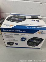 Box of Royal Sovereign Commercial Bill Counter showing product features including counterfeit detection, value counting, speed of 1400 bills per minute, and LCD display.