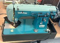 Side view of the vintage StitchMaster zig-zag sewing machine showing the brand plate and overall condition.
