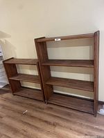 Wooden bookshelves of different sizes placed side by side against a wall on dark wood flooring, showing overall look and size comparison.