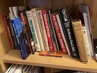 Books lined up on a wooden shelf with visible titles including 'On Call' by Anthony Fauci, 'Red Notice' by Bill Browder, and 'Splendid Isle'.