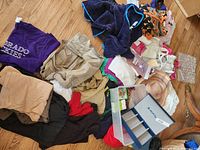 Wide view of clothing assortment, hats, bead necklaces, and blue jewelry organizer box on the floor.
