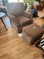 Brown microfiber armchair and ottoman set on wood floor with some surrounding room elements.