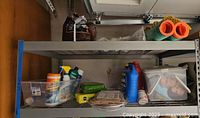 First shelf showing plastic bottles of car cleaning products, cartons with smaller items, and rolls of shrink-wrap.