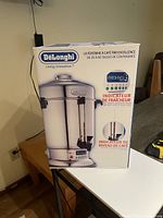 Front view of the boxed DeLonghi Large Percolator Coffee Maker showing product image and key features in French.