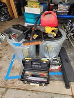 Full view of reciprocating saw, battery, charger, gasoline container, trash cans, toolboxes, broom and other items arranged for sale