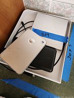 Box with three external hard drives visible; silver devices and one black device with cables