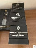 Stack of Forever Flawless Black Diamond anti-aging skin care products showing diamond infused cream and thermal mask boxes.