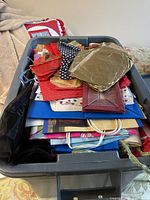 Top view of tub filled with assorted Christmas gift bags, placemats, and some towels visible underneath.