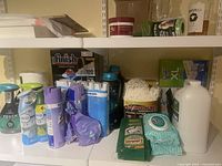Shelf with assortment of household cleaning supplies including sprays, wipes, detergents, and dishwasher tablets.