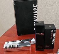 Four IL Makiage waterproof makeup product boxes on a wood surface with the brand name visible.