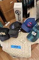 Five kids' hats, new tagged cream cable knit sweater, and boxed DRVSE device arranged on a round table.