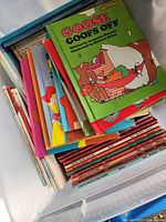 Stack of children's books featuring colorful illustrated covers, including 'Goose Goofs Off'.
