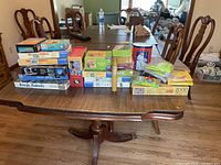 Photo of a large table covered with a variety of boxed kids puzzles and games including large jigsaw puzzle boxes and some game tins and smaller boxes