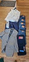 Full view of all items including six pairs of Levi's jeans stacked, JoS. A. Bank suit jacket, white shirt, blue sweater, and a box (unknown contents)