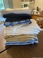 Stack of assorted blankets and sheets showing variety in color and texture