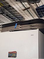 Side view of the four folded metal frame folding chairs stacked horizontally, showing the black and gray frames with padding.