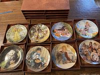 Full set of eight 8.5 inch vintage collector plates from various makers organized in a storage box.