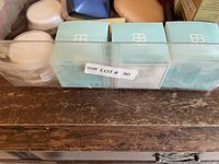 Top view of a container holding boxed turquoise 'BB' items with small white jars on side