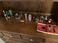 Lot of assorted perfumes and fragrances arranged on wood surface, showing different bottle sizes and some boxed items