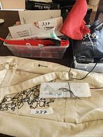Photo showing assorted items including boxes with Drivse showerhead, Sun Visor, Michael Horn M Band, a red neck gaiter, and a beige fabric with embroidery.