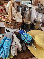 Wide shot showing various gardening gloves, sun hat, wicker basket, lava lamp, and lantern on table surface
