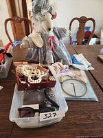 Wide view showing plush mouse, jewelry box with pearl necklaces, sunglasses in plastic bin, wristwatch, and dreamcatcher on table.