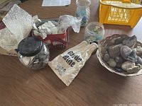 Wide view showing assorted rocks, geodes, sea glass in jars, and bag on a wooden surface