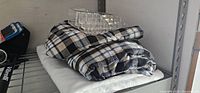 Photo of folded white sheet, plaid sheet or table cloth, and acrylic tray on top