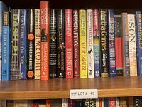 Shelf with an assortment of hardcover and softcover books of various authors and genres, spine titles visible, mostly fiction and non-fiction novels.