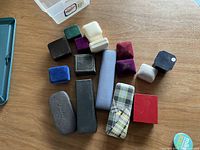 Top down view showing a collection of 14 empty jewelry and glasses cases on a wooden surface.