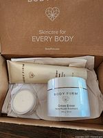 Top view of the open box showing the three creams inside - large jar, large tube, small sample jar. Shows product packaging and cream color.
