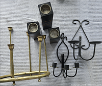 Group view showing brass chandelier frame, black wall sconce, and three black blocks