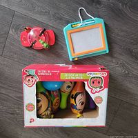 All three items: boxed Cocomelon bowling set, magnetic drawing board, red tabletop game