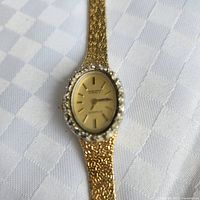 Front view of Dynasty gold-tone wristwatch showing dial, bezel and part of bracelet