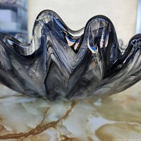 angled view showing wavy rim and swirl pattern of smoky grey glass bowl