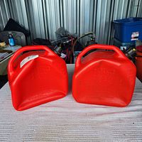 Pair of red 10L gasoline cans showing overall appearance, handles, caps, spouts and dents