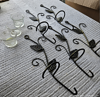 Five wrought iron holders and three glass cups on surface