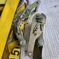 Close-up of two steel ratchet mechanisms attached to yellow straps