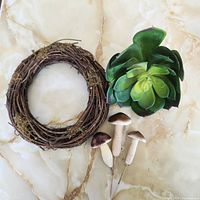 Grapevine wreath, artificial succulent and three mushroom picks laid out on table