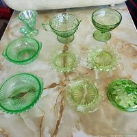 Eight green Depression glass pieces laid out on table
