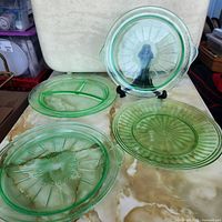All four green depression glass plates displayed