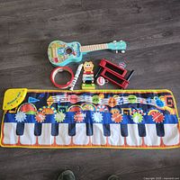 All items laid out: piano mat, guitar, recorder, tambourine, xylophone, clacker, castanet