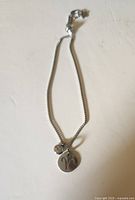Bracelet laid flat showing chain and Aries disc charm