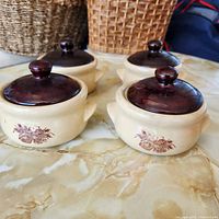 All four lidded beige stoneware onion soup bowls grouped on table